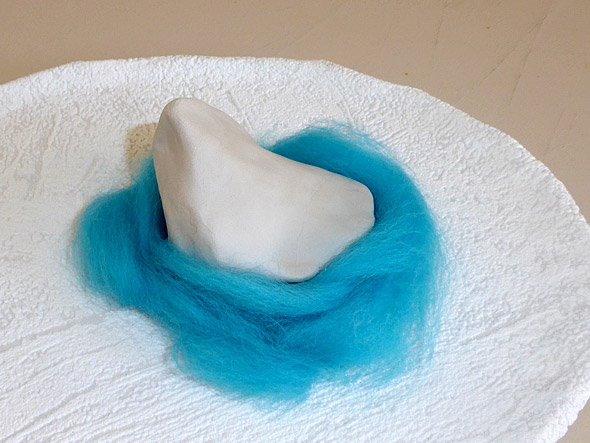 Tonfigur in Nest aus blauer Wolle